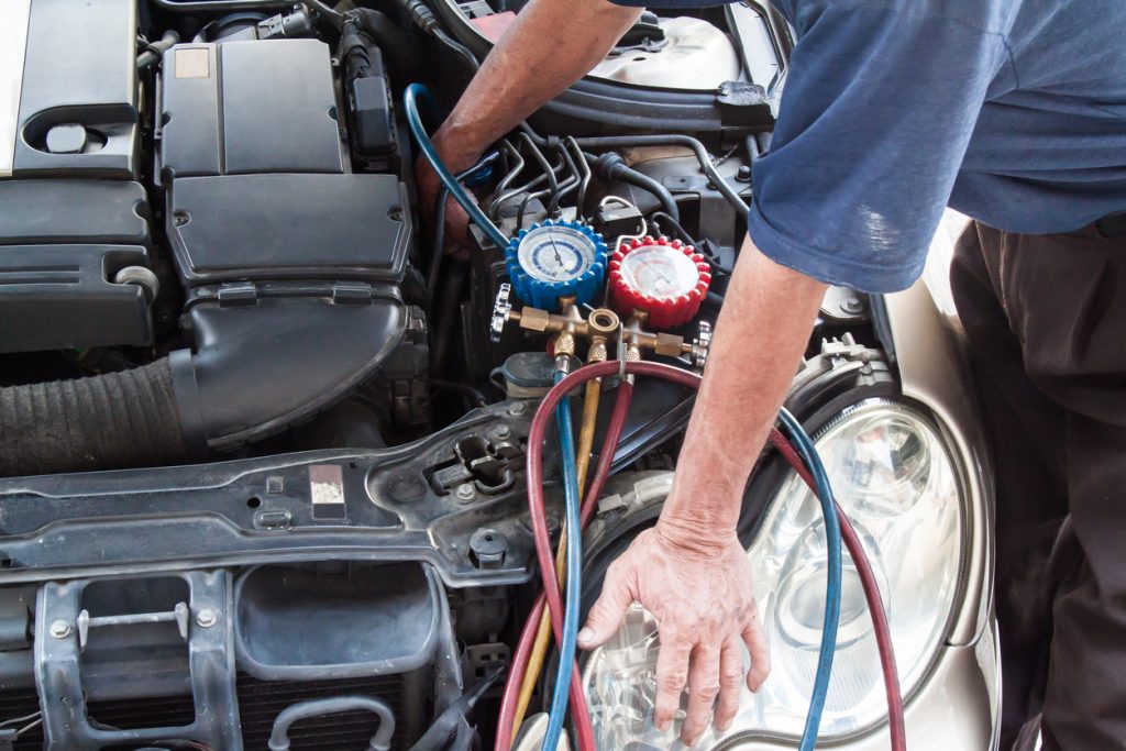 Mechanic with manometer inspecting vehicle heating system