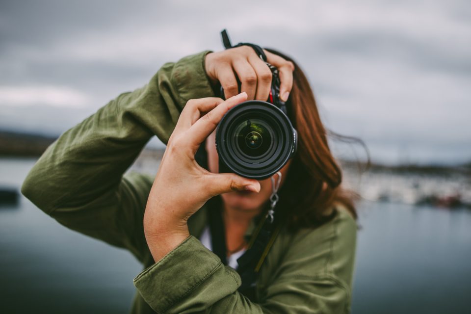 Young artistic woman using DSLR camera