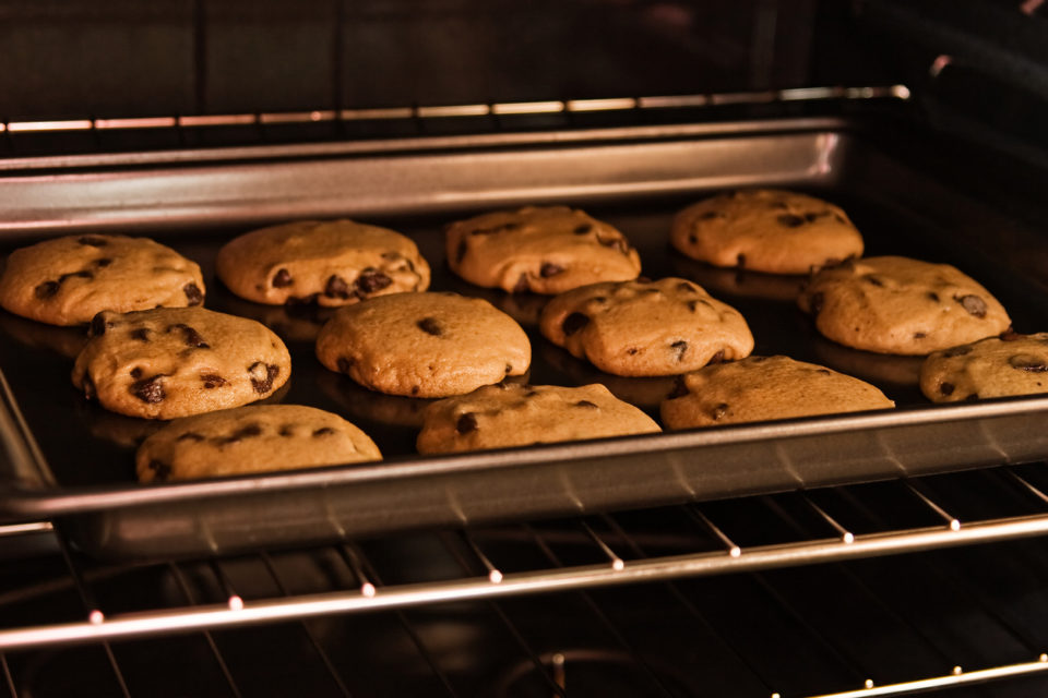 Chocolate chip cookies baking on the oven rack.