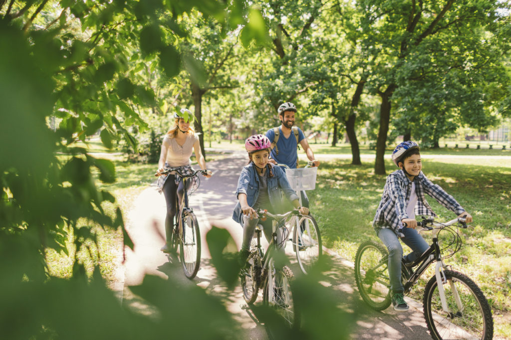 Family riding bikes along a park path