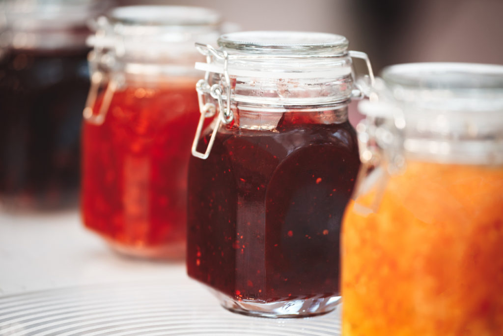 Glass jars with butter and jam on a wooden shelf