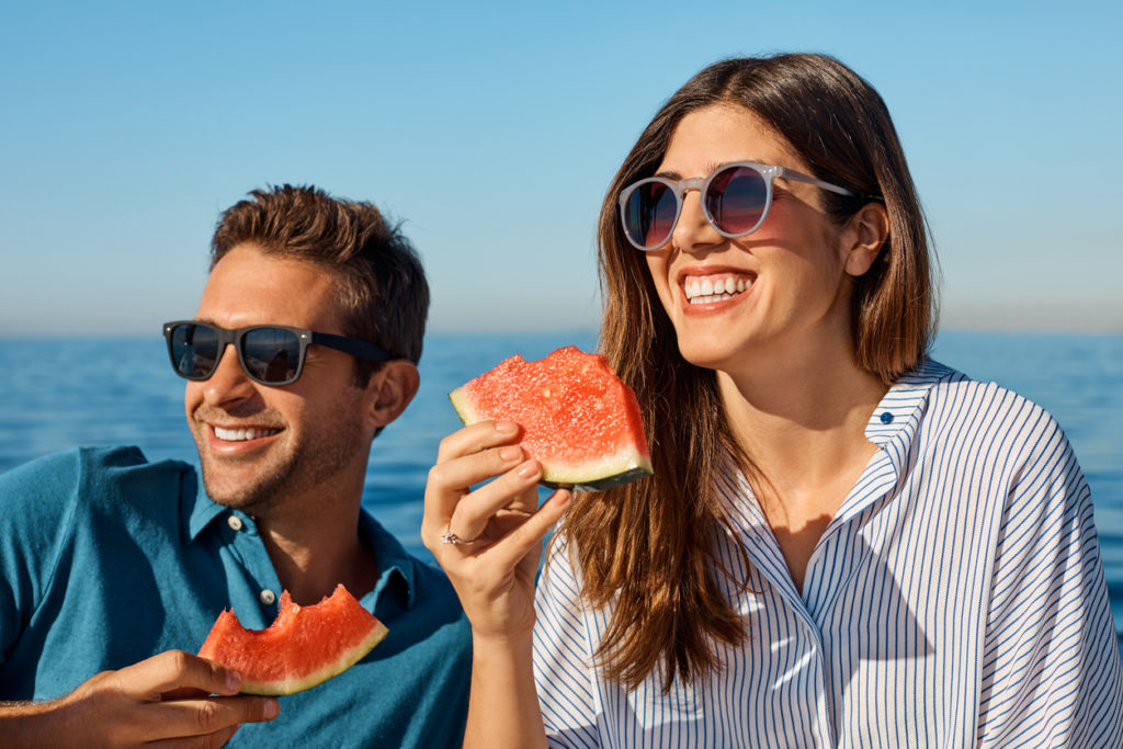 Shot of a happy young couple eating watermelon on a relaxing ocean cruise